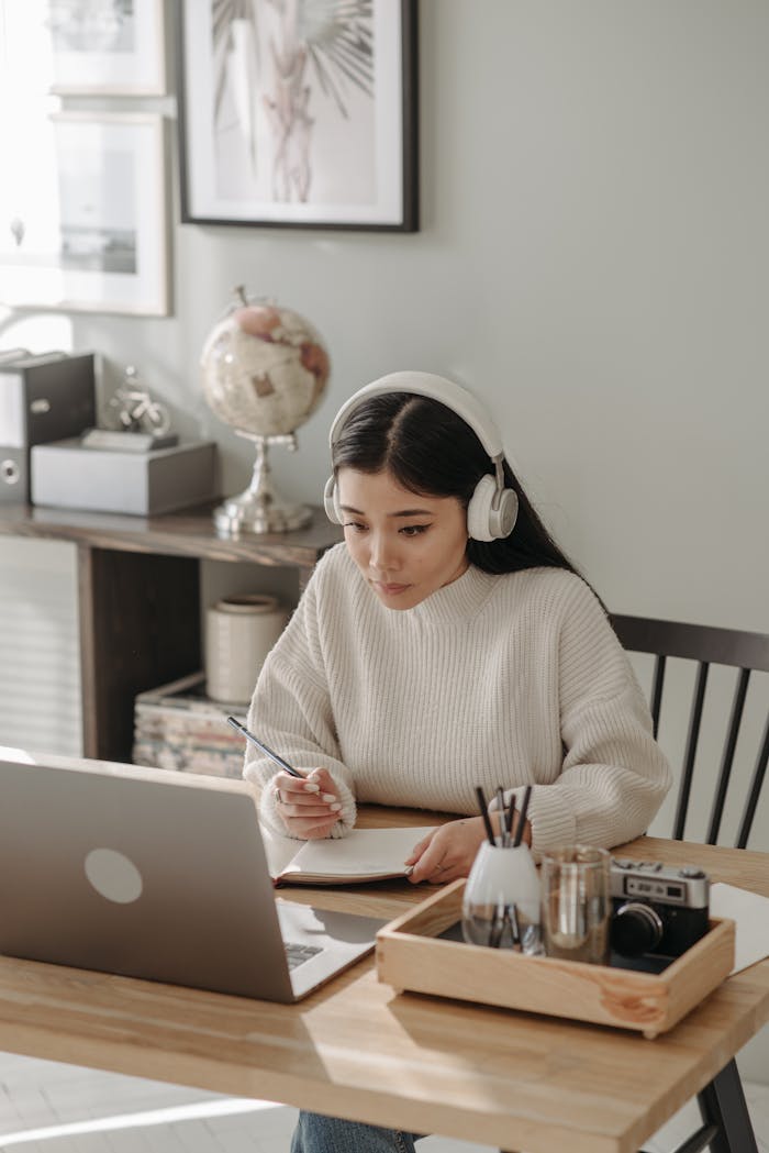 services-03 Woman wearing headphones focused on studying with laptop at home.